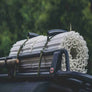 Photograph of a white Mobi-Track mat rolled up and tied to the roof racks of a car