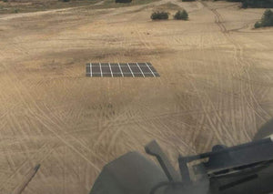 Photo of a Mobi-Heli Portable helipad that has been rolled out on dirt in a rural area.The photo has been taken from a flying helicopter