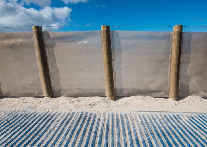 Mobi-Fence on beach with Mobi-Path in the foreground. Bright blue skies in the background.