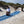 Photograph of an Australian beach with a person in a wheelchair moving along a blue Mobi-Mat that has extended access along the beach.   Mobi-Fence in the background, running along the beach access path.