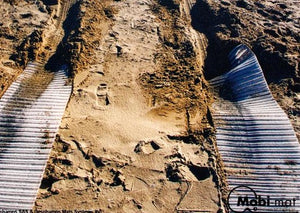 Photo of two white Mobi-Tracks rolled out on sand.