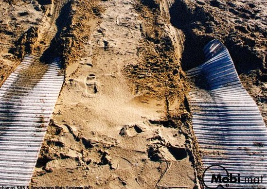 Photo of two white Mobi-Tracks rolled out on sand.